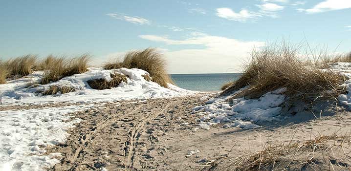 Nedgang til stranden mellem klitter med sol og sne