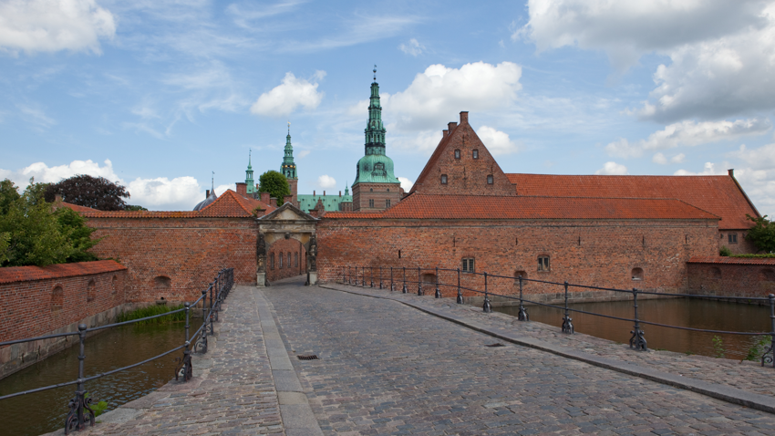 Kasteel Frederiksborg in Hillerod met bakstenen poort over de slotgracht, keienbrug en groene koperen torens